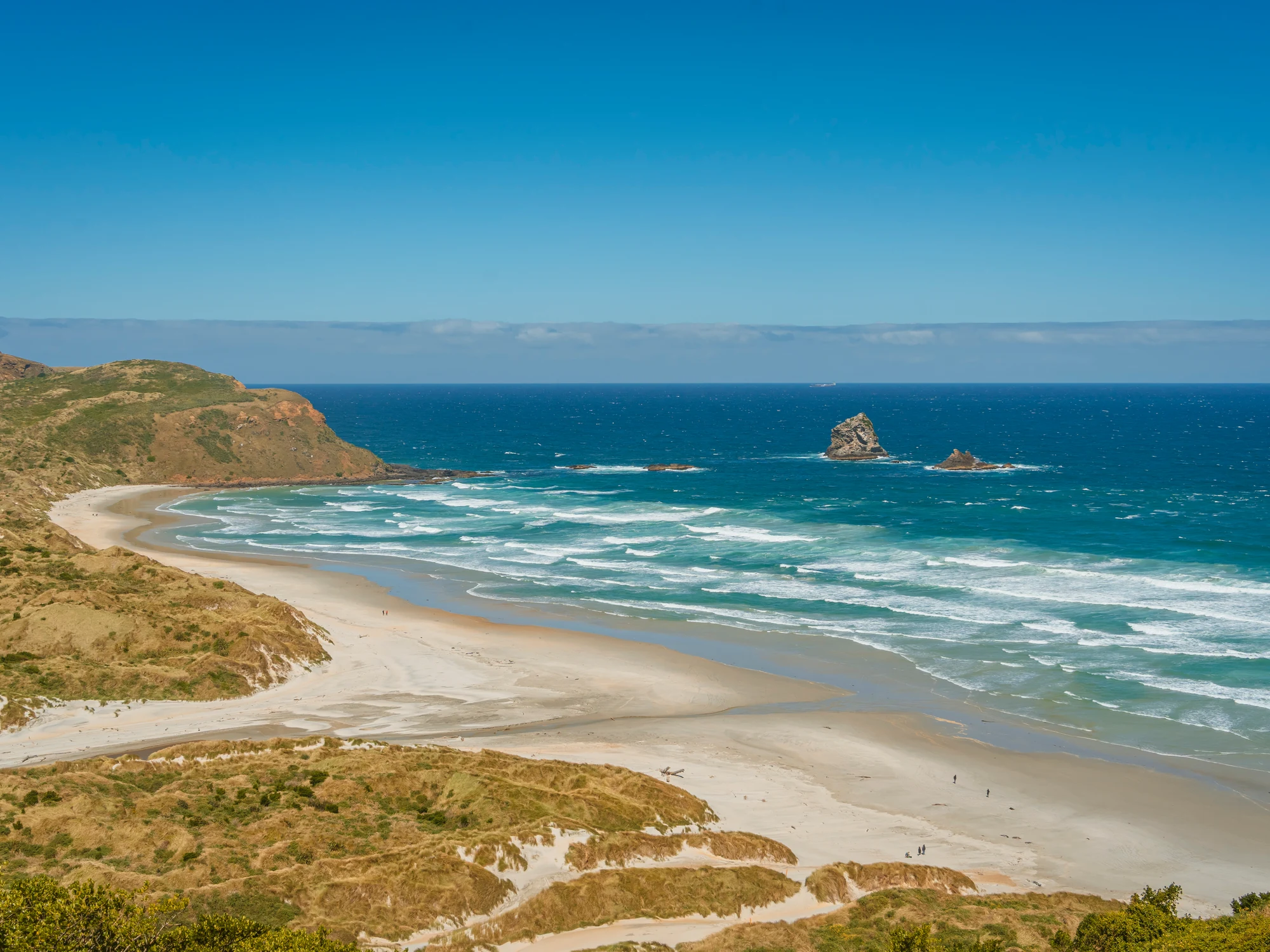 Sandfly Bay beach and distant sea stacks.
