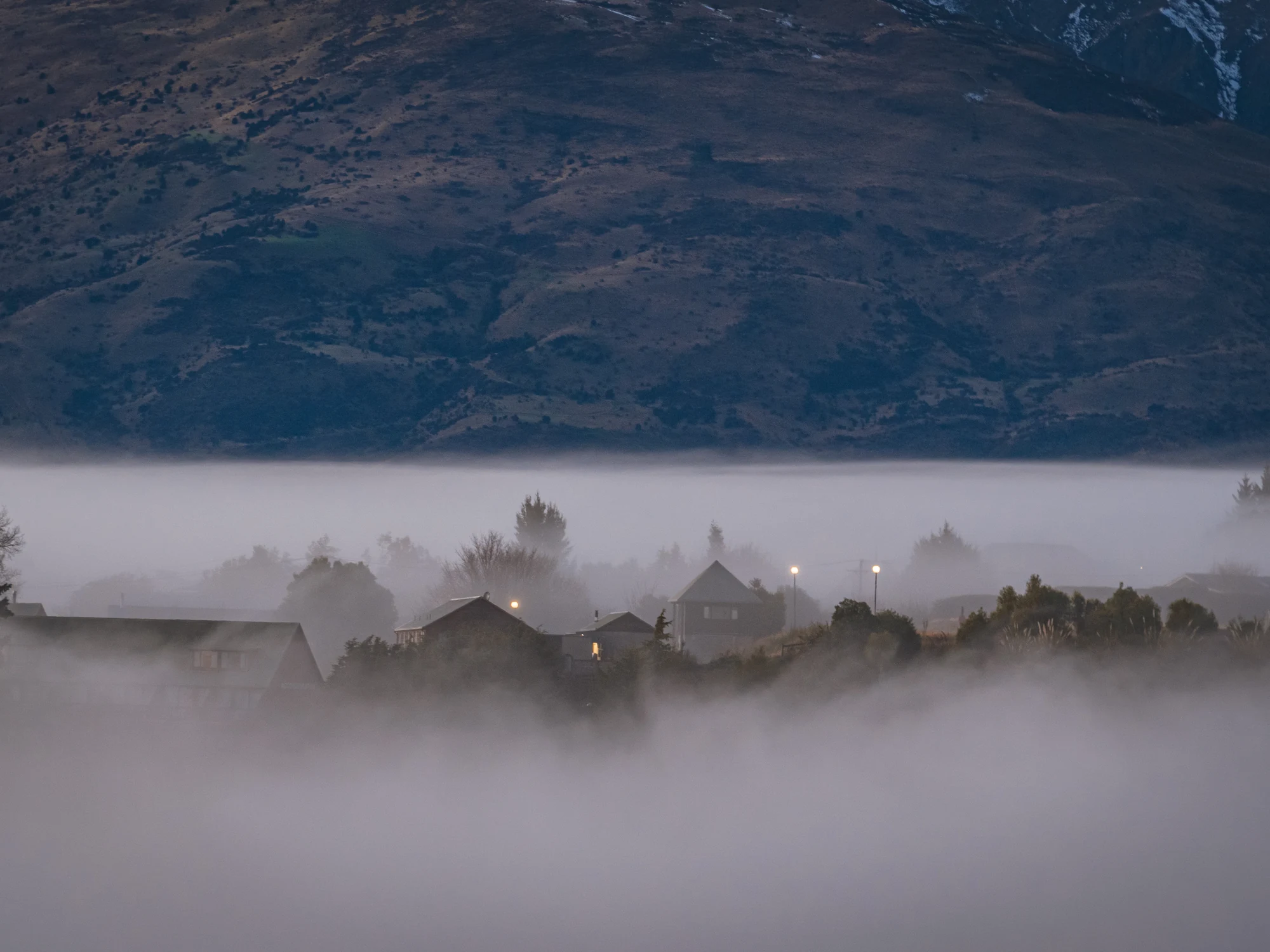 Wānaka rooftops emerging from valley mist