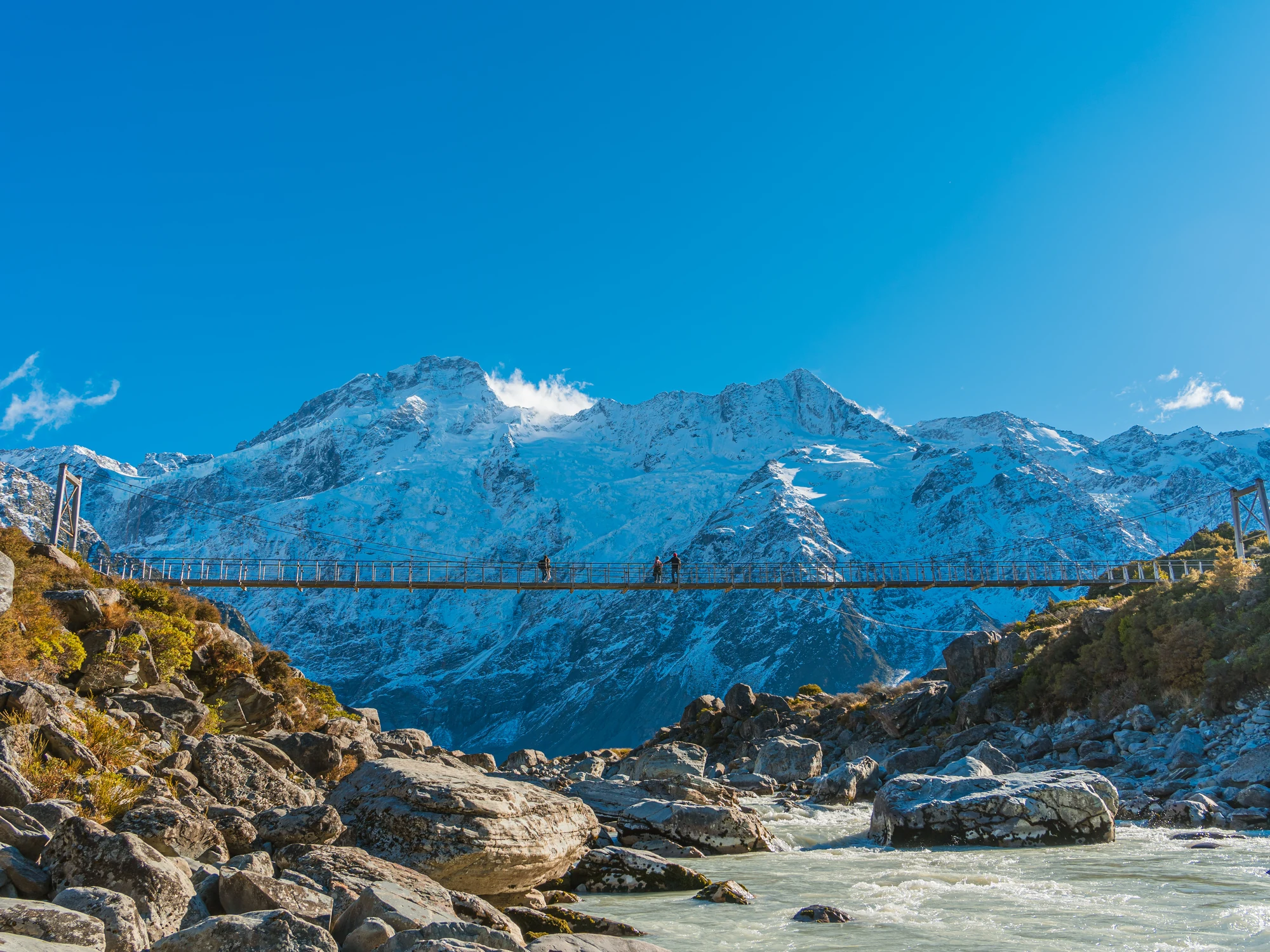 A suspension bridge beneath snowy peaks in Hooker Valley